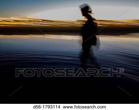 Picture - Woman walking on the beach at dusk, Malvarrosa Beach, Valencia, Spain. Fotosearch