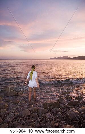 Woman walking on the beach at sunset View Large Photo Image Stock Image - Woman walking on the beach at sunset. Fotosearch