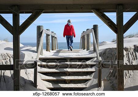 Woman walking on to a beach through a boardwalk shelter Lavalette, New Jersey, USA View Large Photo Image Stock Photo - Woman walking on to a beach through a boardwalk shelter Lavalette, New Jersey, USA. Fotosearch