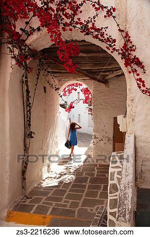 Stock Photograph - Woman walking through an archway in town center Chora, Ios, Cyclades Islands, Greek Islands, Greece, Europe.. Fotosearch