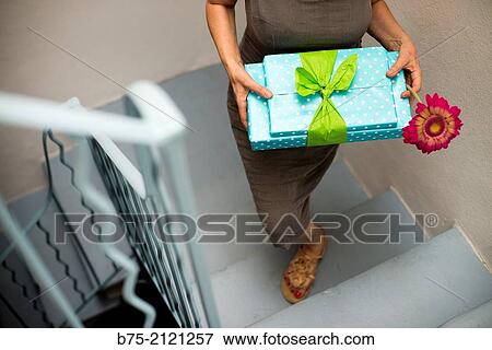 Woman walking up stairs giving some gift packs and a flower View Large Photo Image Stock Photo - Woman walking up stairs giving some gift packs and a flower. Fotosearch