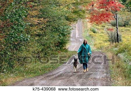 Stock Photo - Woman walking with German shepherd dog. Fotosearch