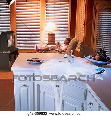 Woman watches TV while kitchen sink overflows. View Large Photo Image Stock Image - Woman watches TV while kitchen sink overflows.. Fotosearch