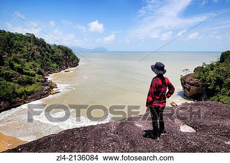 Woman watching the South China sea from a lookout on the Telok Pandan Kecil trail. Malaysia, Borneo, Sarawak, Bako National Park. Model Released. View Large Photo Image Picture - Woman watching the South China sea from a lookout on the Telok Pandan Kecil trail. Malaysia, Borneo, Sarawak, Bako National Park. Model Released.. Fotosearch