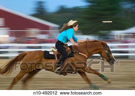 Woman, wearing a hat, competing in a horse racing contest in a corral at a fair View Large Photo Image Stock Image - Woman, wearing a hat, competing in a horse racing contest in a corral at a fair. Fotosearch