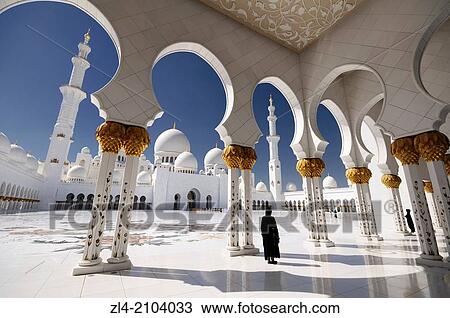 Stock Image - Woman wearing an abaya in the mosque courtyard. United Arab Emirates, UAE, Abu Dhabi, Sheikh Zayed Grand Mosque.. Fotosearch