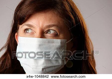 Stock Image - Woman wearing surgical mask to protect herself from contracting contagious influenza viruses like H1N1 Swine Flu. Fotosearch
