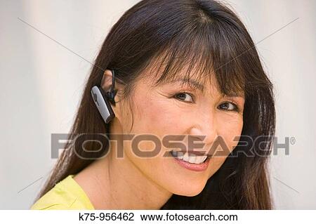 Stock Image - Woman wearing telephone earpiece. Fotosearch