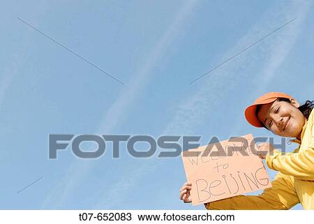 Stock Image - Woman wearing the Chinese Olympic Uniform colors - sign reads? Welcome to Beijing?. Fotosearch