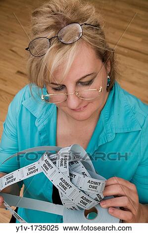 Woman wearing two pairs of glasses looking at a roll of tickets View Large Photo Image Stock Photography - Woman wearing two pairs of glasses looking at a roll of tickets. Fotosearch
