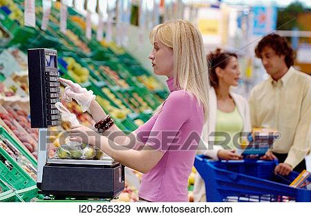 Stock Photo - Woman weighing fruit at supermarket. Fotosearch