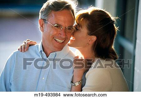 Picture - woman whispering in a man's ear. Fotosearch