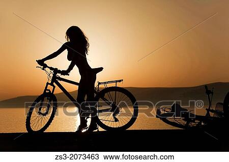 Woman with a bicycle near the sea at sunset, Koufonissi, Cyclades Islands, Greek Islands, Greece, Europe. View Large Photo Image Stock Image - Woman with a bicycle near the sea at sunset, Koufonissi, Cyclades Islands, Greek Islands, Greece, Europe.. Fotosearch