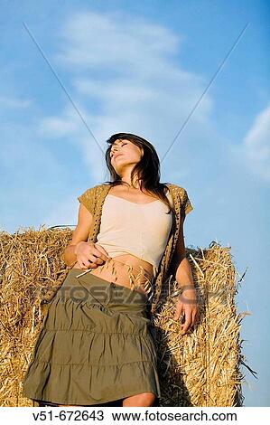 Stock Image - Woman with a branch of cereal in a field of wheat. Fotosearch