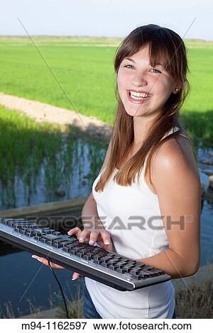 Stock Photo - Woman with a computer keyboard in her hands. Fotosearch