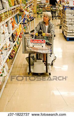 Woman with a foot injury rides a scooter with a large basket for shopping in a store, Ontario, Canada View Large Photo Image Stock Photo - Woman with a foot injury rides a scooter with a large basket for shopping in a store, Ontario, Canada. Fotosearch