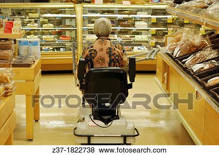 Stock Photo - Woman with a foot injury rides a scooter for shopping in a store, Ontario, Canada. Fotosearch