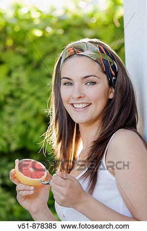 Woman with a piece of fruit smiling and looking at camera View Large Photo Image Stock Photography - Woman with a piece of fruit smiling and looking at camera. Fotosearch