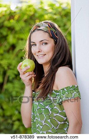 Woman with an apple outdoor looking at camera View Large Photo Image Stock Photo - Woman with an apple outdoor looking at camera. Fotosearch