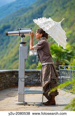 Woman with an umbrella watching a telescope in ticino switzerland. View Large Photo Image Stock Photo - Woman with an umbrella watching a telescope in ticino switzerland.. Fotosearch