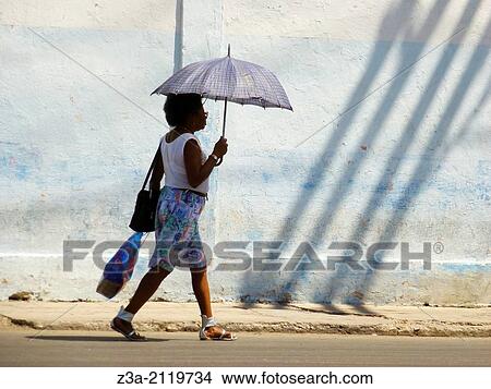 Woman with bag and umbrella walking in the streets of Havana, Cuba. View Large Photo Image Picture - Woman with bag and umbrella walking in the streets of Havana, Cuba.. Fotosearch