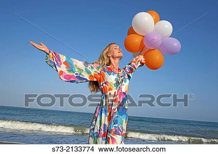 Picture - Woman with balloons in the beach. Fotosearch