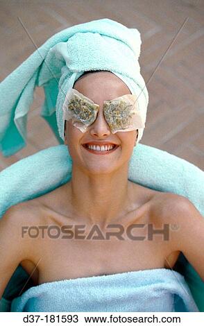 Stock Image - Woman with camomile tea bags on her eyes. Fotosearch