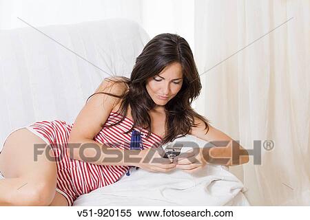 Stock Photography - Woman with cell phone at home. Fotosearch