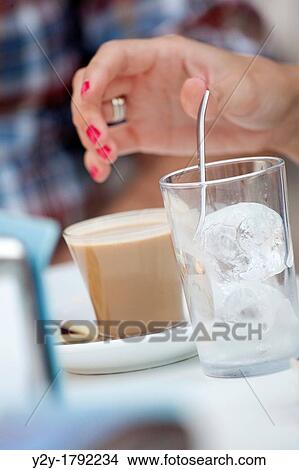 Picture - Woman with coffe and a glass with ice. Fotosearch