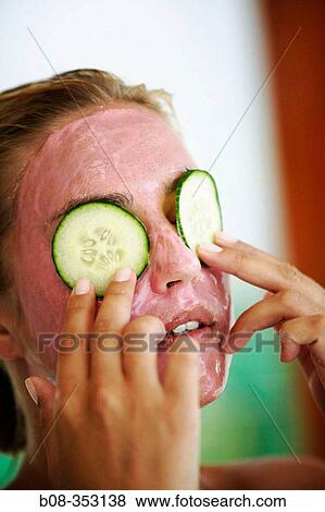 Stock Photo - Woman with facial mask and cucumber. Fotosearch