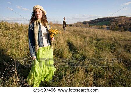 Woman with flowers standing on hilltop with man watching View Large Photo Image Stock Photograph - Woman with flowers standing on hilltop with man watching. Fotosearch