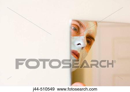 Woman with green facial mask looking in the mirror in the bathroom View Large Photo Image Stock Photo - Woman with green facial mask looking in the mirror in the bathroom. Fotosearch