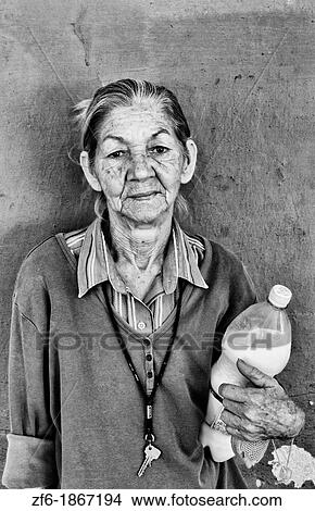 Picture - Woman with her ration milk from government on first of month in small town outside of Havana Cuba. Fotosearch