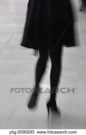 Stock Image - woman with high heels shoes walking in street road in city town. Fotosearch