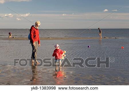 Stock Photo - Woman with Kid in Red on P? rnu Beach in Estonia, Europe. Fotosearch