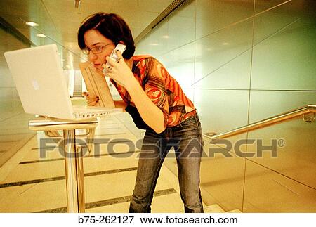 Stock Photo - Woman with laptop in a corridor. Fotosearch