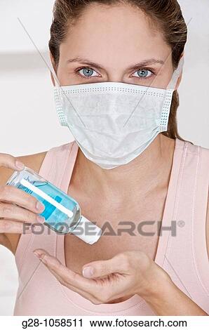 Woman with mask desinfecting her hands with a blue desinfectant View Large Photo Image Stock Image - Woman with mask desinfecting her hands with a blue desinfectant. Fotosearch