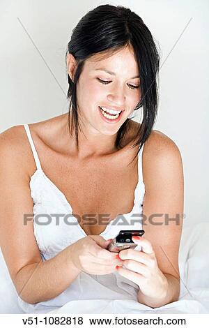 Woman with mobile in bed View Large Photo Image Stock Photo - Woman with mobile in bed. Fotosearch