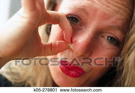 Woman with pained look holding a nose ring View Large Photo Image Stock Image - Woman with pained look holding a nose ring. Fotosearch