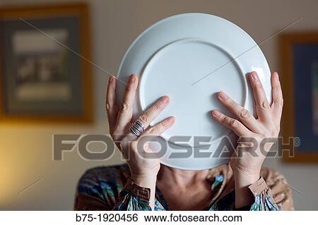Woman with plate in hands covering her face View Large Photo Image Stock Photograph - Woman with plate in hands covering her face. Fotosearch