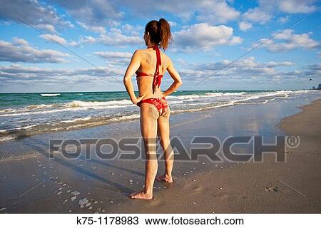 Woman with sand on her behind standing on the shoreline View Large Photo Image Stock Image - Woman with sand on her behind standing on the shoreline. Fotosearch
