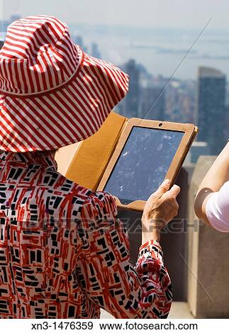Woman with Tablet PC, Cityscape, Manhattan, from the Top of the Rock observation deck of Rockefeller Center, New York City. USA. View Large Photo Image Stock Photo - Woman with Tablet PC, Cityscape, Manhattan, from the Top of the Rock observation deck of Rockefeller Center, New York City. USA.. Fotosearch