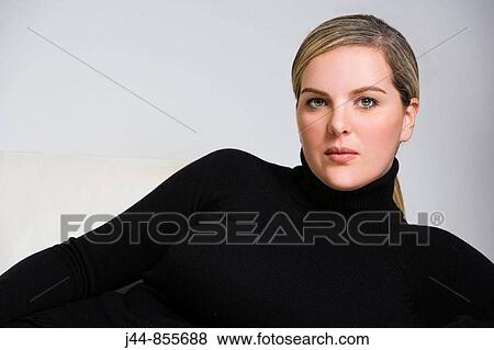 Stock Photo - Woman with turtle neck sweater laying on sofa, portrait. Fotosearch