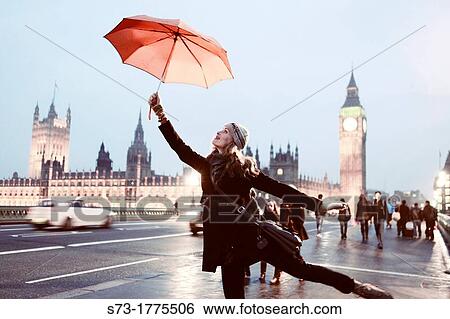 Stock Photograph - Woman with umbrella and view of the Houses of Parliament and Westminster Bridge, London, England. Fotosearch