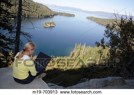 Woman working on a laptop above a lake View Large Photo Image Stock Image - Woman working on a laptop above a lake. Fotosearch