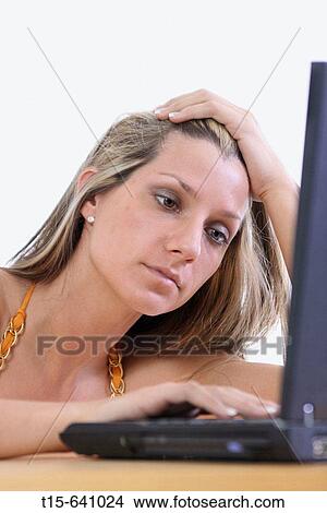 Picture - Woman working on her laptop exhausted and tired. Fotosearch