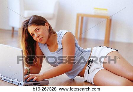 Woman working with a portable computer on the floor View Large Photo Image Stock Photo - Woman working with a portable computer on the floor. Fotosearch