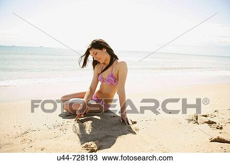 Stock Image - Woman writing on the sand summer beach. Fotosearch
