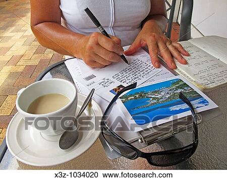 Stock Image - Woman writing postcards on holiday at Airlie Beach in Queensland. Fotosearch