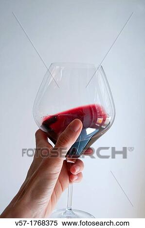 Stock Photography - Woman's hand holding a glass of red wine, tasting it. Fotosearch